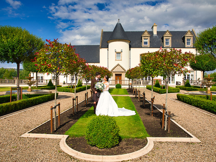 Bride and groom standing in venue gardens